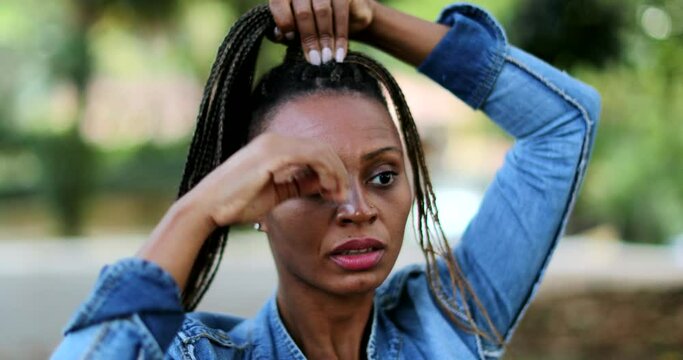 African woman adjusting dread hair outside