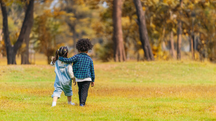 two diverse mixed race children boy and girl play together in park during autumn
