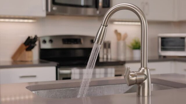 Water Running from a Kitchen Faucet. kitchen sink island running water into the sink with appliances in background
