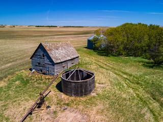 An aerial view of the old, abandoned farms and buildings that were built by the first farming settlers of Saskatchewan. These structures have been forgotten and left to be reclaimed by nature 