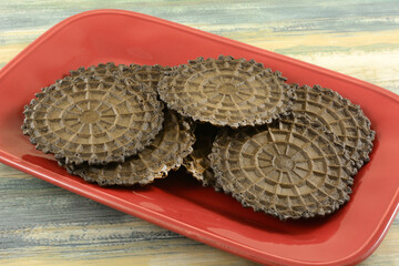 Chocolate waffle biscuit or cookie snacks on red serving plate on table