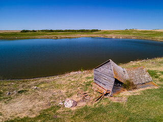 An aerial view of an old farm house built by the first settlers of Saskatchewan. This house has been abandoned, forgotten to time and has collapsed 