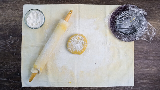 Raw sugar cookie dough on a pastry cloth with a rolling pin and flour, ready for rolling out
