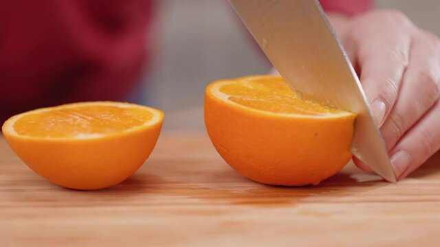 Slicing an Orange Half Close Up. female slices an orange half into a quarter wedge close up