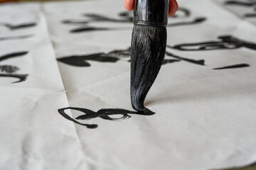A calligrapher is writing calligraphy characters with a large brush, a close-up of the brush....