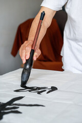 A calligrapher is writing calligraphy characters with a large brush, a close-up of the brush. Translation: The heights are too cold