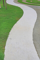 Fototapeta na wymiar Cement path walkway with green grass beside in the garden
