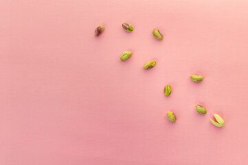 Peeled pistachio kernels isolated on a pink background being chased by their shell similar to the...