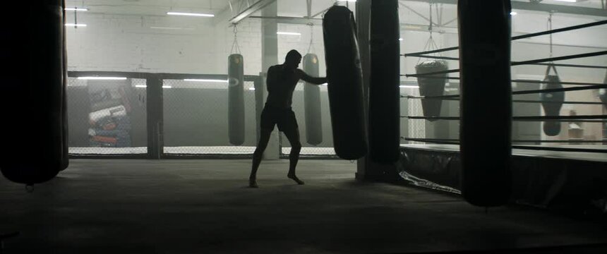 HANDHELD WIDE Caucasian male professional boxer practicing punches and kicks in the boxing gym. Shot with 2x anamorphic lens