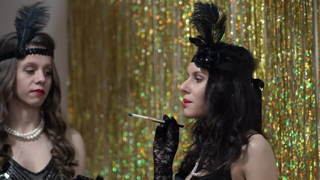 Vintage retro Great gatsby young women lighting a chiigarette with a mouthpiece on a throwback retro roaring twenties pary