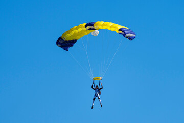 Parachutist with  yellow and blue parachute