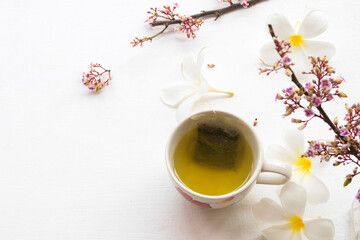 Obraz na płótnie Canvas herbal health drinks hot green tea with flowers arrangement flat lay style on background white 
