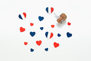 Hearts in the colors of the French flag and a french champagne bottle cork on a light background, top view, Bastille Day and French National Day concept