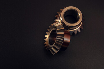 Two bevel gears on a black background, advertising of manufactured products at a gear-cutting enterprise.