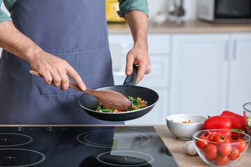 Man frying vegetables in kitchen, closeup