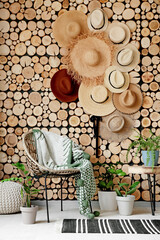 Wicker armchair and stylish hats hanging on wooden wall