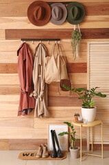 Hangers with clothes and hats on wooden wall