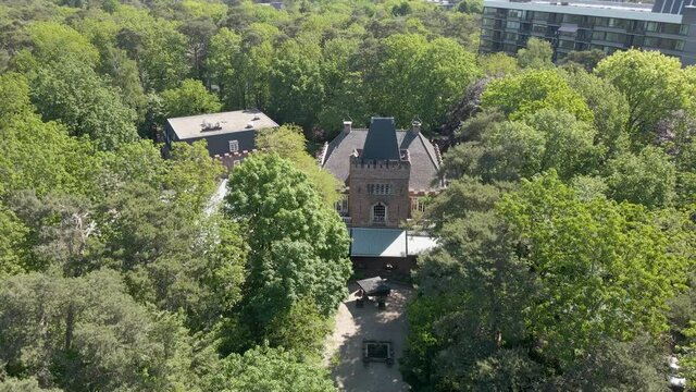 Jib up of classic manor hidden in green forest - close