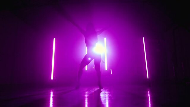 Young woman relaxed dancing sexy dance alone in dark purple studio. Lady moving actively her body and hair to the music rhythm. Slow motion.