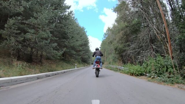 Biker stunt ride biike on mountain rural road and do wheelie on motorcycle