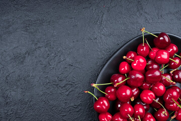 Red cherries in black plate