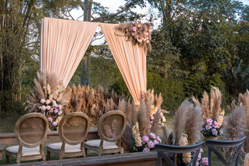 A rustic garden wedding setup, with wooden chairs and benches, and a simple altar arch and aisle...