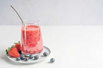 Refreshing vegan smoothie made from pureed ripe sweet juicy strawberries and blueberries served in...