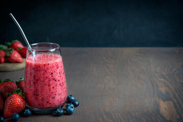 Refreshing sweet smoothie made of fresh juicy strawberries and blueberries served in drinking glass...