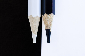 Black and white pencils on a black-red background closeup