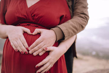 hands on belly of pregnant woman dressed in red.