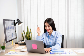 Obraz na płótnie Canvas Asian woman working on a laptop with a cheerful and happy smile while working at the office