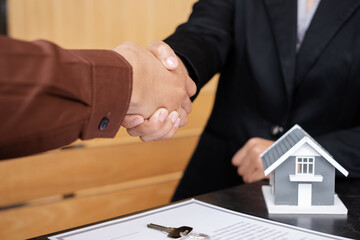 Businessmen and brokers real estate agents shake hands after completing negotiations to buy houses insurance and sign contracts. Home insurance concept
