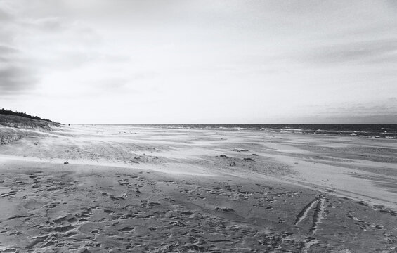 Strand in Dębki in Polen an der Ostsee im Winter mit vielen Spuren im Sand am menschenleeren Strand. Einsamer, wunderschöner Sandstrand in schwarzweiss monochrom.