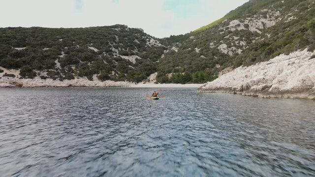 Couple kayaking on the sea, blue cave beach, Cres Island, Croatia. Fast aerial pullback