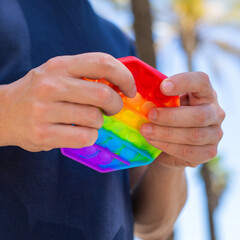 Man with rainbow anti stress pop it toy, outdoors