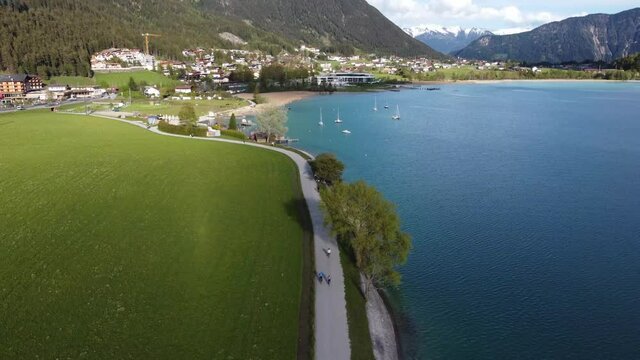 Promenade for bikers and pedestrians by beautiful lake in mountains. Bike lane in heart of Alps with beautiful views around.
