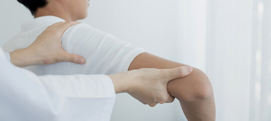 Female physiotherapists provide physical assistance to male patients with shoulder injuries massage their shoulders for muscle recovery in the rehabilitation center. Physiotherapy concepts
