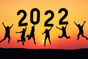 Silhouette friends jumping and holding number 2022 on sunset sky abstract background at tropical beach. Happy new year and holiday celebration concept.