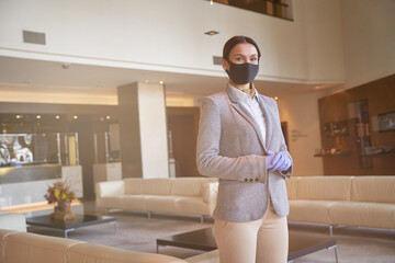 Beautiful young woman in fabric mask in the hotel hall