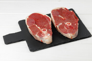 Raw lamb steak on board on white wooden table