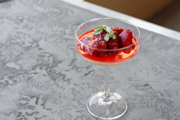 Fresh strawberry fruit parfait in glass cup on gray surface
