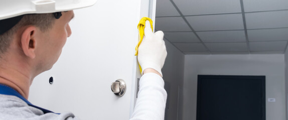 after oiling the door mechanism, the master in protective gloves and a hard hat, wipes the edges of...