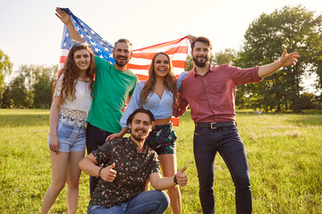Group of young people with american flag celebrate america independence day standing in park.