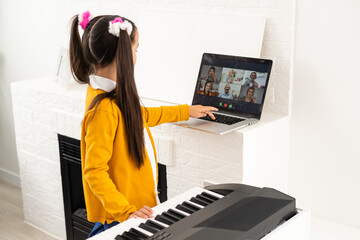 Little girl watching online lesson tutorial how to learn a synthesizer