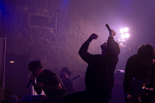 Silhouette Of Rock Band With Vocalist Show Hands Raised Up Performing On Stage, Rock Concert Show Set Up.