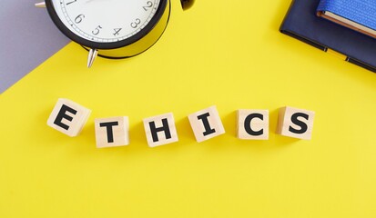 ETHICS word concept made with building blocks, yellow background