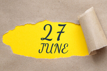 june 27. 27th day of the month, calendar date.Hole in paper with edges torn off. Yellow background is visible through ragged hole.Summer month, day of the year concept