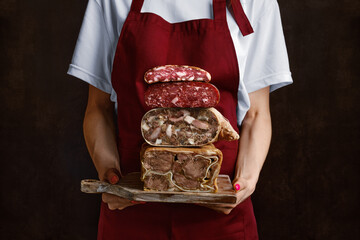 Woman holds board in hand with boiled pork meat roll, beef tongue roll and homemade sausage