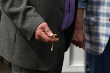 a cigarette in the hand of an elderly man