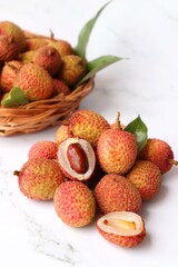 Bunch of fresh ripe lychee fruit with green leaves on white background. Exotic or tropical litchi fruit. Lichi. Copy space.